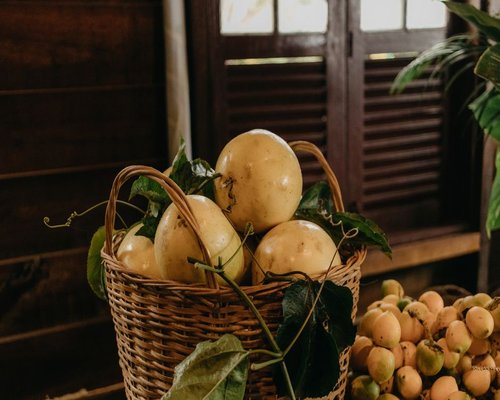 A rustic wooden basket filled to the brim with ripe Colombian lulos and maracuyás on a table